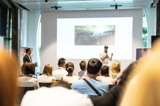 Male speaker giving a talk in conference hall at business event. Audience at the conference hall. Business and Entrepreneurship concept. Focus on unrecognizable people in audience.