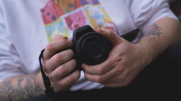 Young man photographer holds camera. Photographer concept.