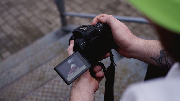 Young man photographer holds camera. Photographer concept. Swivel camera screen.