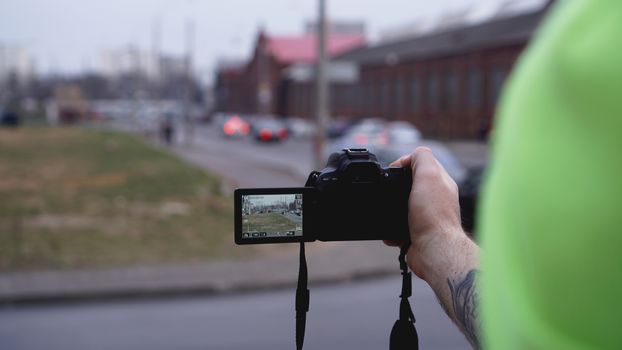 Young man photographer holds camera. Photographer concept. Swivel camera screen.