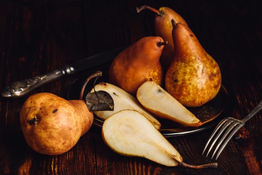 Few Golden Pears on Wooden Table with Sliced One, Fork and Knife.
