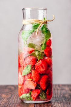 Bottle of Water Infused with Fresh Strawberry and Basil Leaves and Ice Cubes. Vertical Orientation.