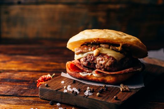 The Casanova Burger on Cutting Board. Cheeseburger with Beef Patty, Wisconsin Swiss Cheese, Ham, Sauteed Mushrooms, Dijon Mustard, Mayonnaise and Potato Roll. Wooden Background and Copy Space.