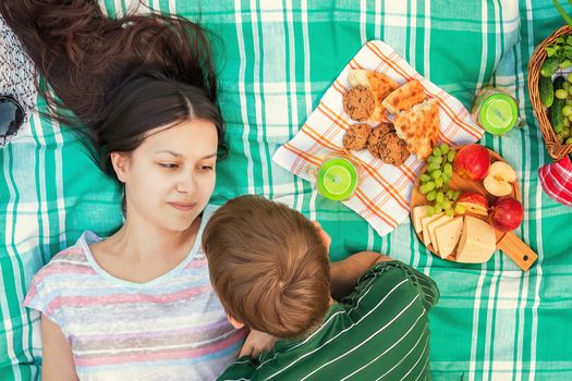 Young loving couple resting on a picnic on a summer day.