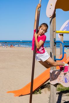 Little girl playing in a playground on the beach