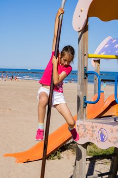 Little girl playing in a playground on the beach