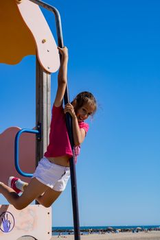 Little girl playing in a playground on the beach