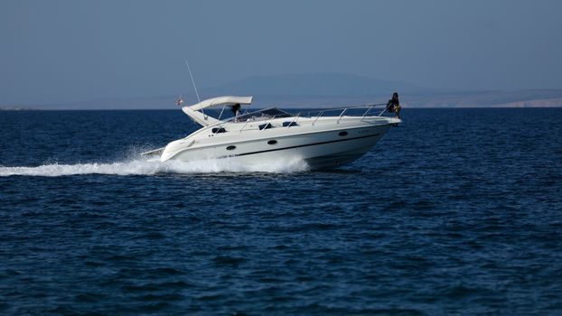 Small launch boat with people, blue sea and sky