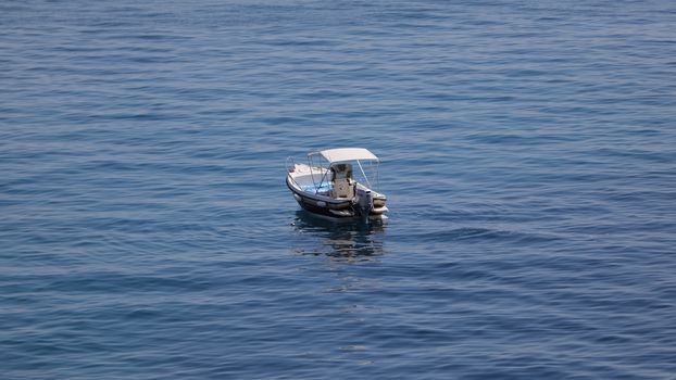 Small launch boat with people, blue sea and sky