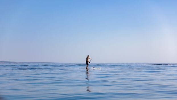 A standup paddleboarding, supsurfing man in the Adriatic sea in Croatia