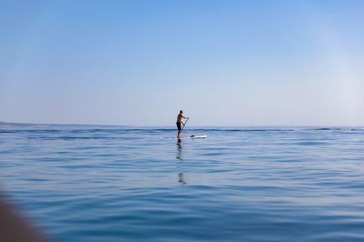 A standup paddleboarding, supsurfing man in the Adriatic sea in Croatia