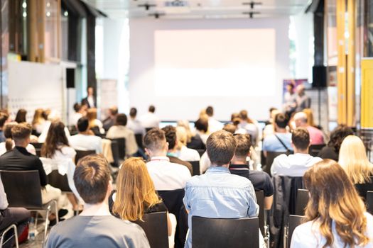 Talk in conference hall at business event. Audience at the conference hall. Business and Entrepreneurship concept. Focus on unrecognizable people in audience. Copy space on empty white screen.