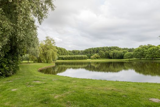 big garden in a park in holland with green trees and small pond 