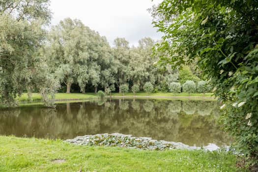 big garden in a park in holland with green trees and small pond 