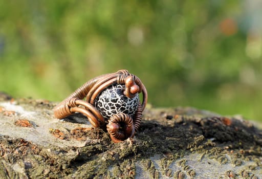 a Hand made copper ring with semiprecious stone on the wooden background