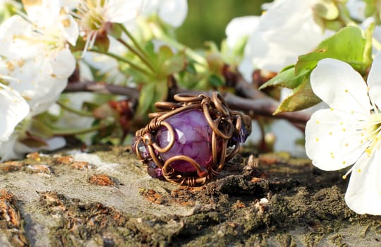 a Hand made copper ring with violet semiprecious stone on the wooden background