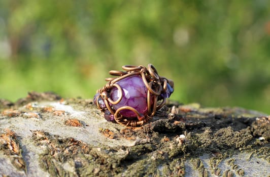 the Hand made copper ring with violet semiprecious stone on the wooden background