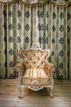 Old armchair in the room near the curtained window