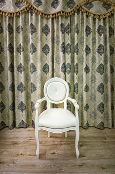 Old armchair in the room near the curtained window