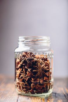 Jar of Star Anise Fruits and Seeds on Wooden Table. Vertical Orientation with Copy Space.