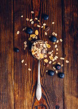 Spoonful of Granola and Scattered Blueberry on Wooden Table. View from Above. Vertical Orientation.