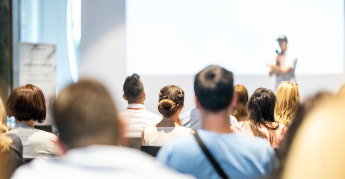 Male speaker giving a talk in conference hall at business event. Audience at the conference hall. Business and Entrepreneurship concept. Focus on unrecognizable people in audience.