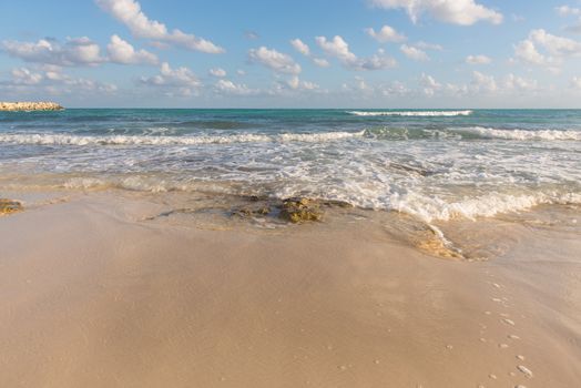 Granite rocks lay in  sand on a Cancun beach at sunset, Mexico.