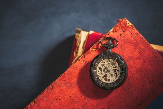 Pocket watch and old book on cement floor. Top view and copy space for text. Concept of time and education.