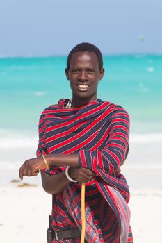 Traditonaly dressed masai black man on Paje beach. Maasai warrior on picture perfect tropical sandy beach on Zanzibar, Tanzania, East Africa.