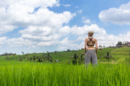 Relaxed sporty female traveler enjoying pure nature at beautiful Jatiluwih rice fields on Bali. Concept of sustainable tourism, nature enjoyment, balanced life, freedom, vacations and well being.