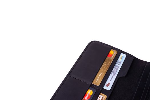 24.01.2019 Ukraine, Kyiv. A part of handmade black leather wallet isolated on white background closeup. A lot of plastic cards in purse pockets. Editorial use only.