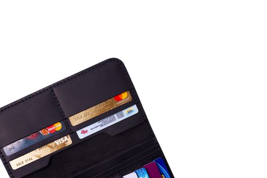 24.01.2019 Ukraine, Kyiv. A part of handmade black leather wallet isolated on white background closeup. A lot of plastic cards in purse pockets. Editorial use only.