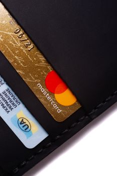 24.01.2019 Ukraine, Kyiv. A part of handmade black leather wallet isolated on white background closeup. A lot of plastic cards in purse pockets. Editorial use only.