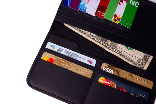 24.01.2019 Ukraine, Kyiv. A part of handmade black leather wallet isolated on white background closeup. A lot of plastic cards in purse pockets. Editorial use only.