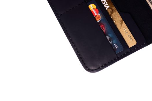 24.01.2019 Ukraine, Kyiv. A part of handmade black leather wallet isolated on white background closeup. A lot of plastic cards in purse pockets. Editorial use only.