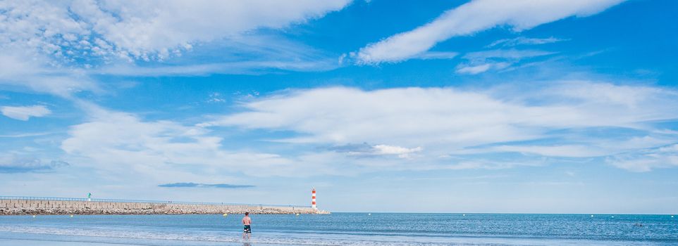 Lighthouse of Port-La-Nouvelle in red and white on cloudy sky in Occitanie, France