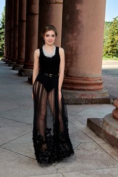 Young woman in sexy transparent black dress near the ancient building. Vintage building. Fashion woman. Young woman modern portrait.