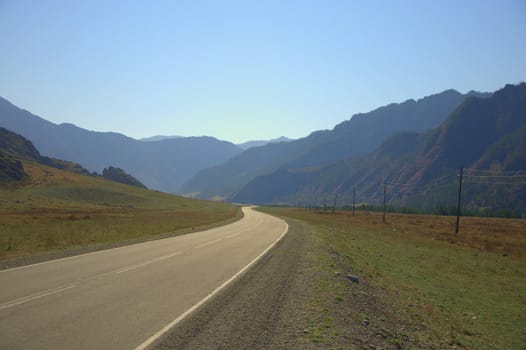 Asphalt road loop between the mountains goes beyond the horizon. Altai, Siberia, Russia.