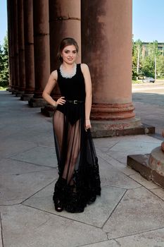 Young woman in sexy transparent black dress near the ancient building. Vintage building. Fashion woman. Young woman modern portrait.