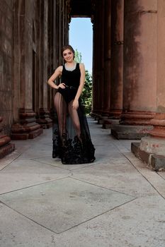 Young woman in sexy transparent black dress near the ancient building. Vintage building. Fashion woman. Young woman modern portrait.