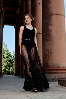 Young woman in sexy transparent black dress near the ancient building. Vintage building. Fashion woman. Young woman modern portrait.