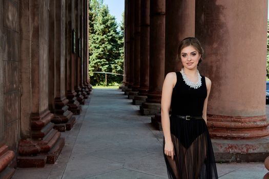 Young woman in sexy transparent black dress near the ancient building. Vintage building. Fashion woman. Young woman modern portrait.