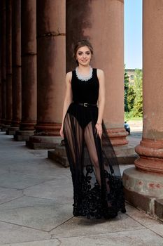 Young woman in sexy transparent black dress near the ancient building. Vintage building. Fashion woman. Young woman modern portrait.