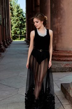 Young woman in sexy transparent black dress near the ancient building. Vintage building. Fashion woman. Young woman modern portrait.