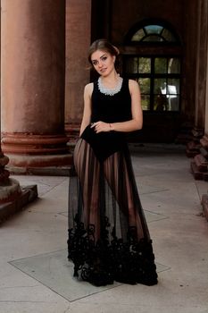 Young woman in sexy transparent black dress near the ancient building. Vintage building. Fashion woman. Young woman modern portrait.