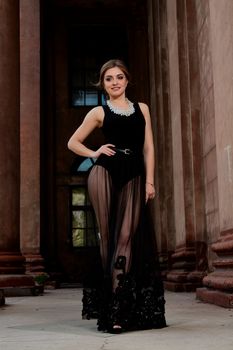 Young woman in sexy transparent black dress near the ancient building. Vintage building. Fashion woman. Young woman modern portrait.