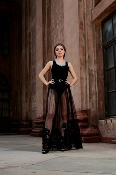 Young woman in sexy transparent black dress near the ancient building. Vintage building. Fashion woman. Young woman modern portrait.