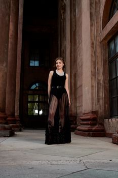 Young woman in sexy transparent black dress near the ancient building. Vintage building. Fashion woman. Young woman modern portrait.