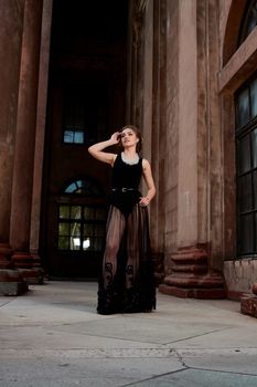 Young woman in sexy transparent black dress near the ancient building. Vintage building. Fashion woman. Young woman modern portrait.