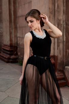 Young woman in sexy transparent black dress near the ancient building. Vintage building. Fashion woman. Young woman modern portrait.